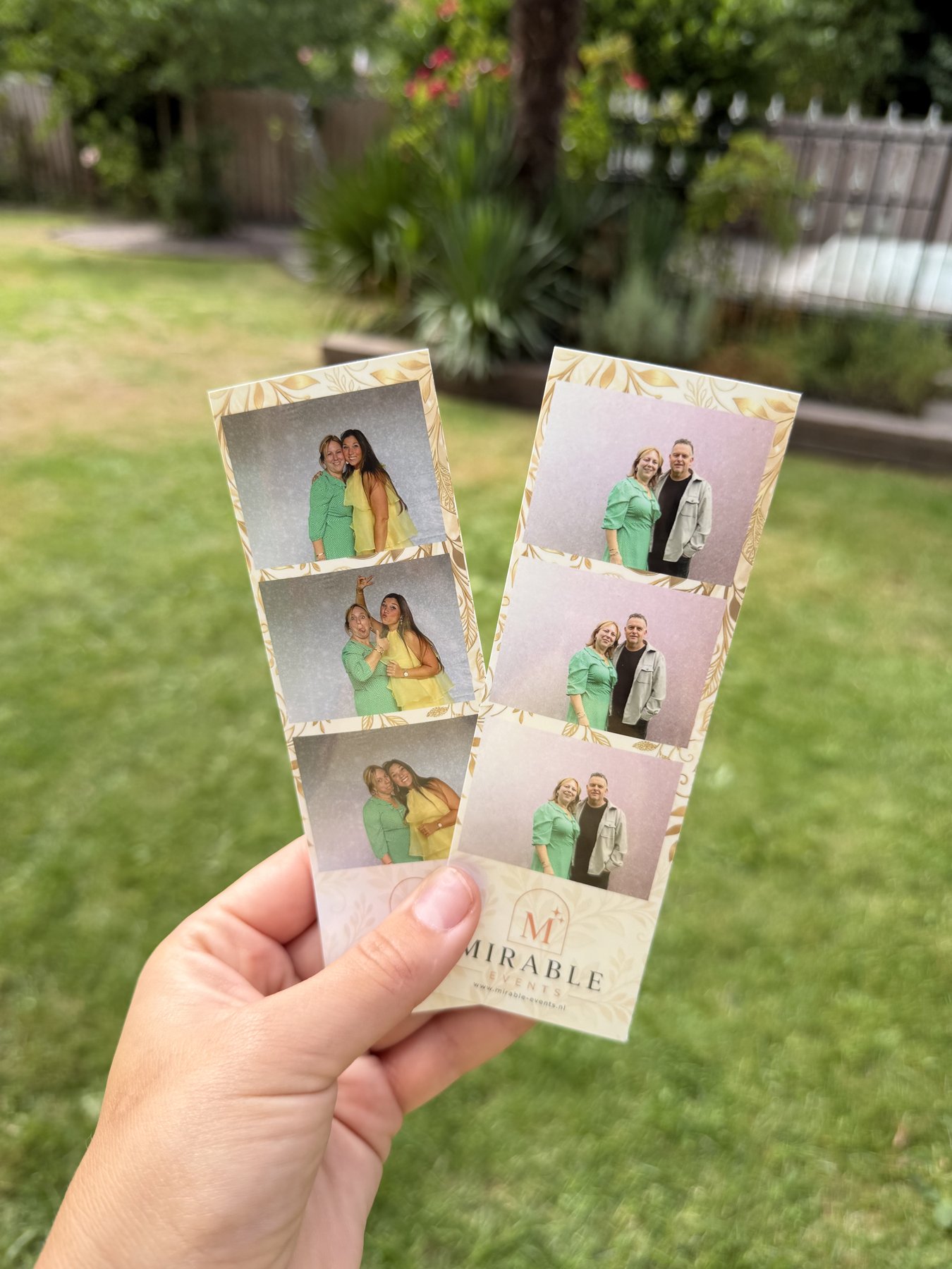 Hand houdt twee geprinte Mirable Events fotostrips vast in de tuin